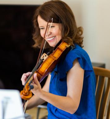 Joanna Owen smiling while seated playing the violin